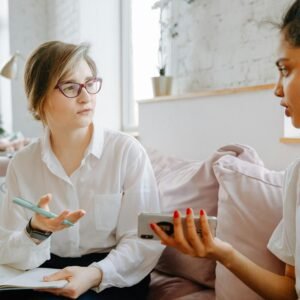 Therapist and client discussing mental health issues during a counseling session in a bright, cozy room.