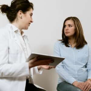 A doctor consults with a pregnant patient discussing healthcare options in a medical facility.